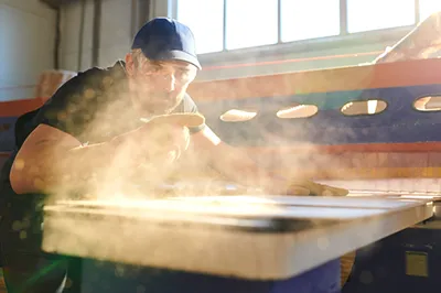 man cutting wood in a dusty workshop