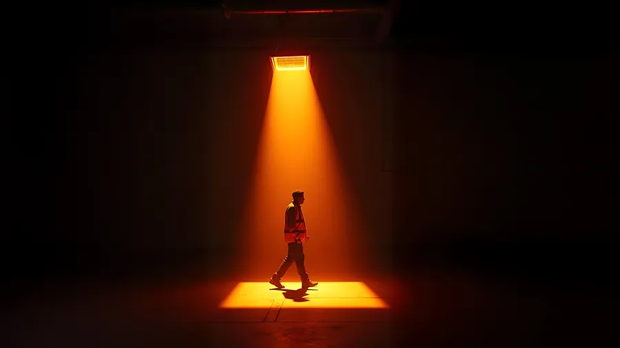 Warehouse worker walking through the orange glow of a heater